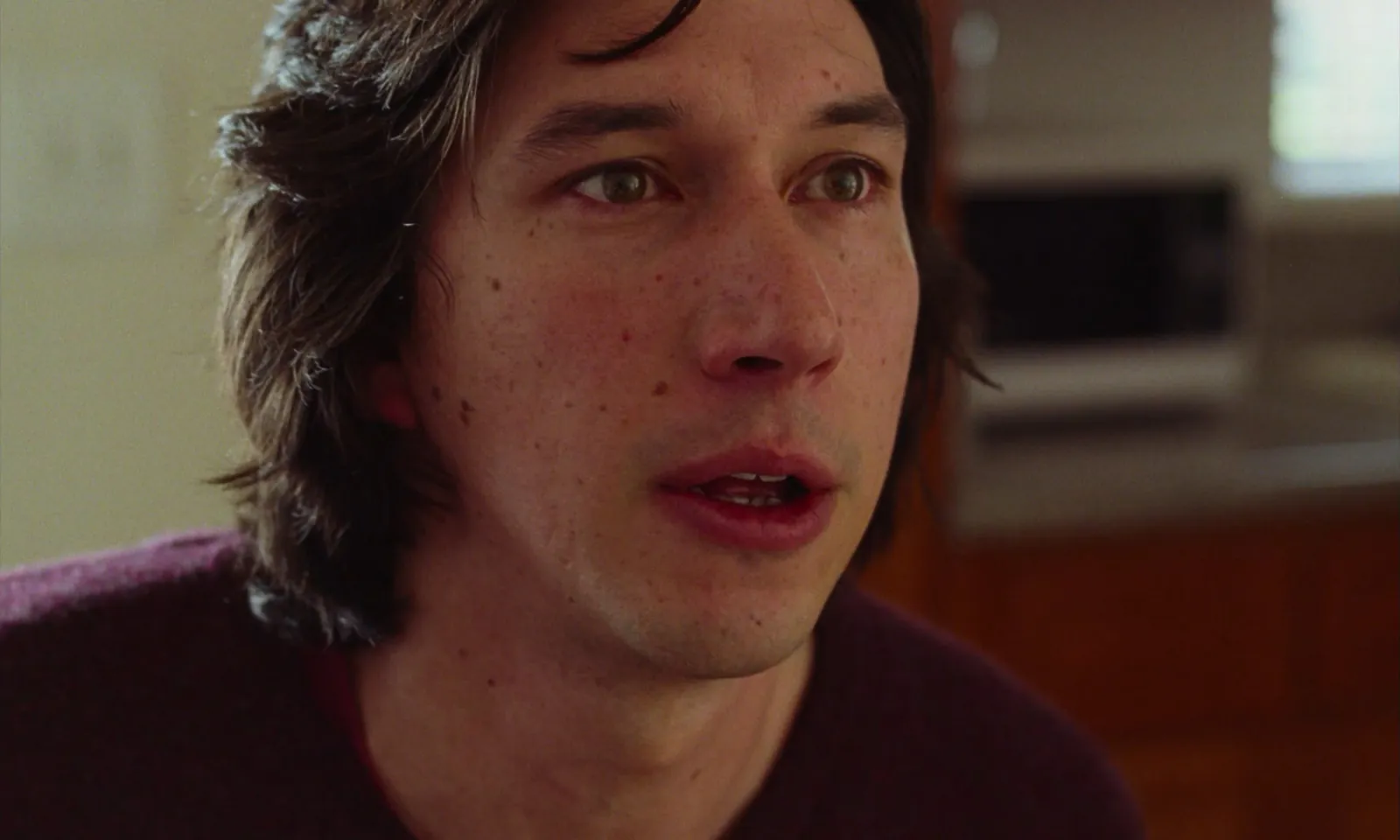 A man's face, mouth slightly open, watching something with curiosity