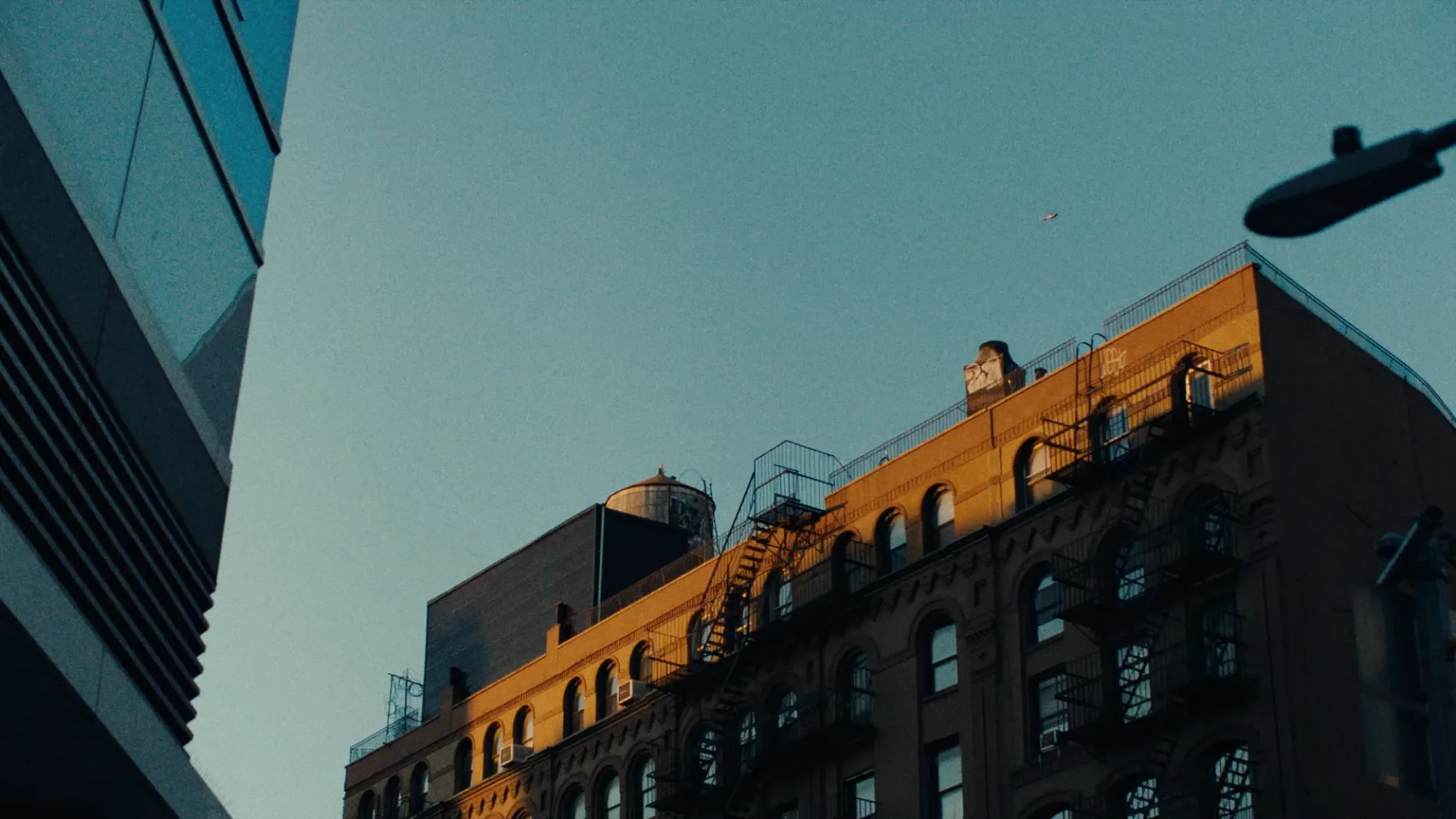 A rooftop catching the last sun against a blue sky